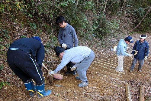 木製ステップの修繕をする塾生たち。左から長谷さん、宮部さん、西野さん、講師の森昌槻さん（グリーンバレー）とジュリアンさん。